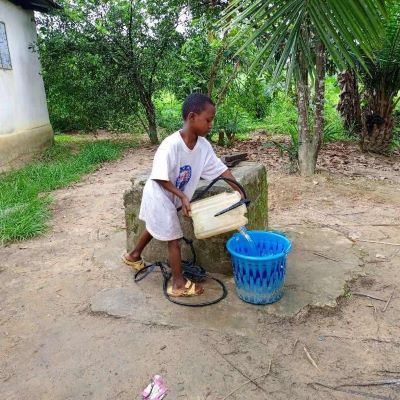 Village girl collecting water from an old water source